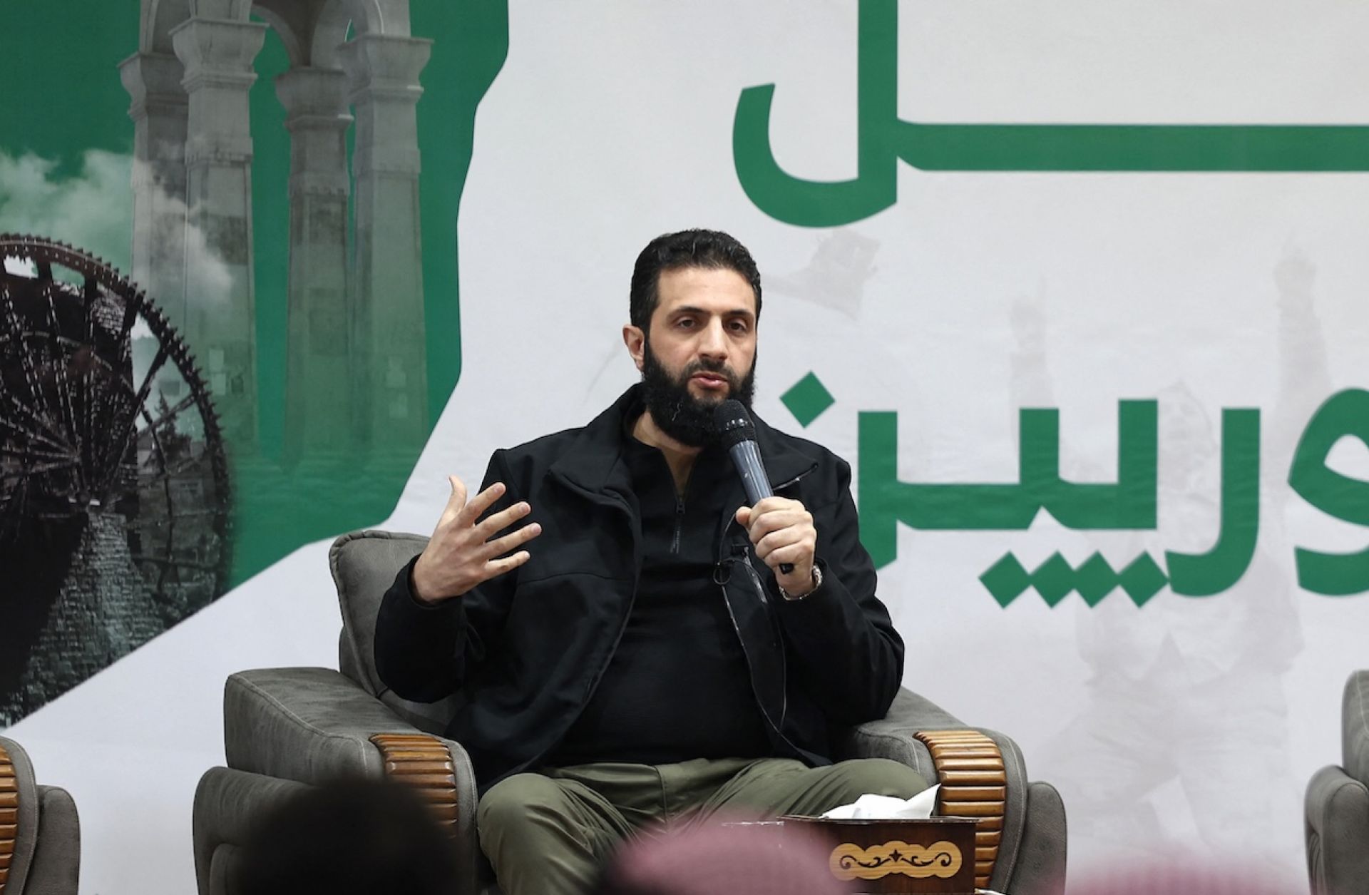 Abu Mohammed al-Golani (C), the head of Syria's leading insurgent group Hayat Tahrir al-Sham, speaks during a press conference near Syria's northern Bab al Hawa border crossing with Turkey late on March 12, 2024.