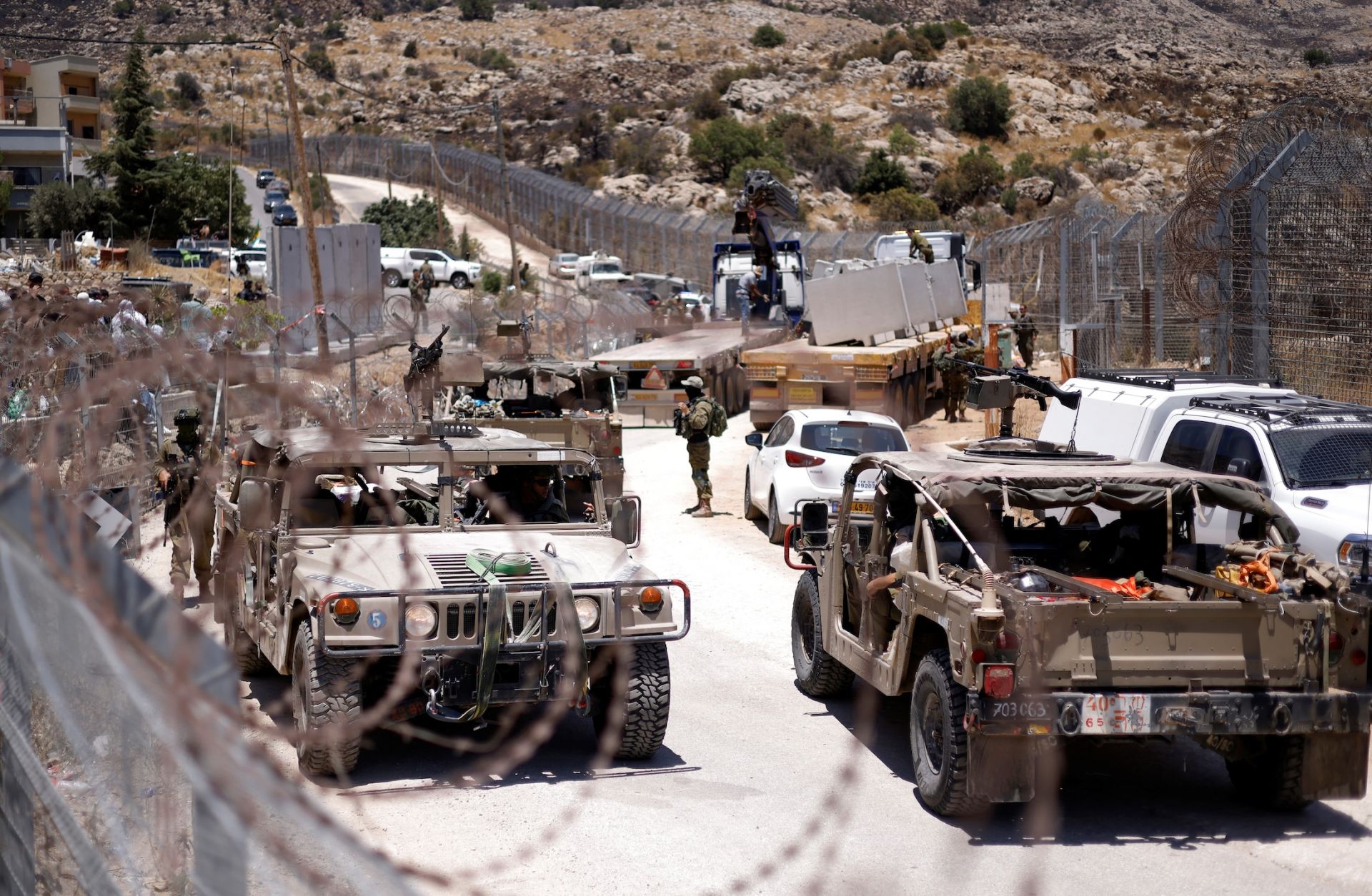 Israeli military vehicles drive along a border fence, near the town of Majdal Shams, in the Israeli-annexed Golan Heights, on July 17, 2025. 