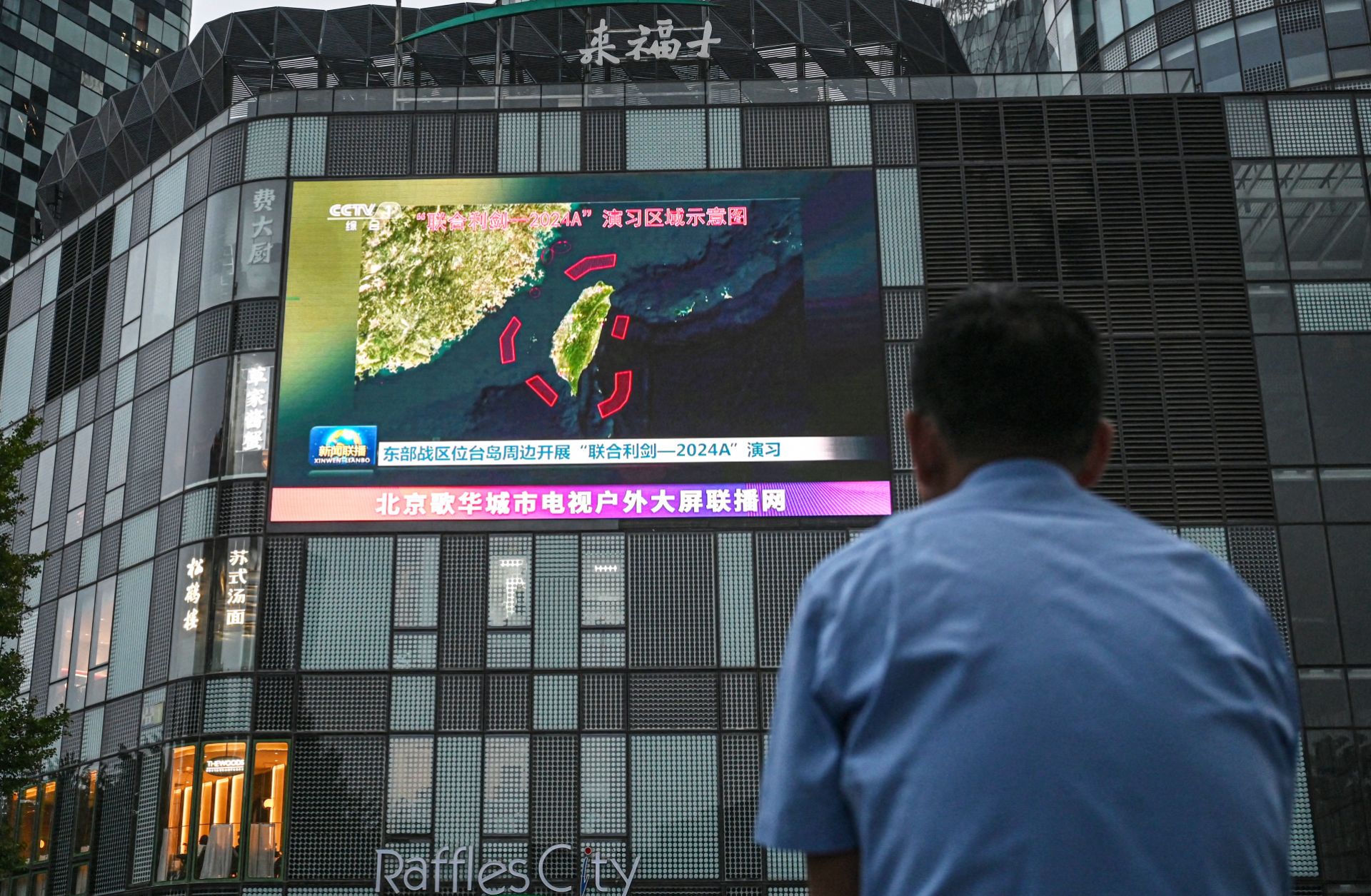An outdoor screen shows news coverage of China's military drills around Taiwan, in Beijing, China, on May 23, 2024. 