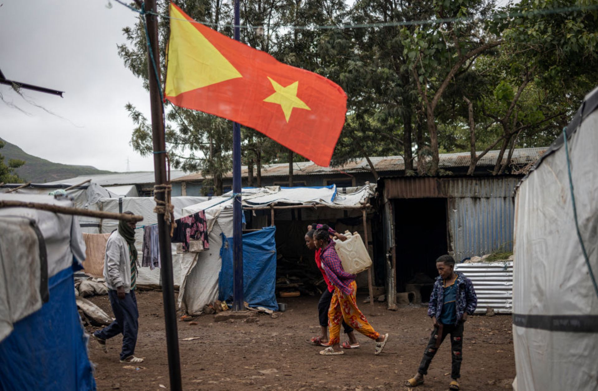 Internally displaced people walk past the Tigrayan flag at the Tsehaye camp in Ethiopia's Shire, Tigray region, on July 16, 2024. 