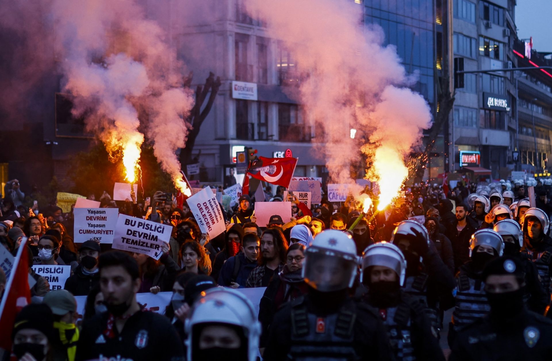 Escorted by riot police, students burn flares on March 24, 2025, as they march along the streets of Istanbul, Turkey, in support of the city's mayor after he was arrested on corruption charges. 