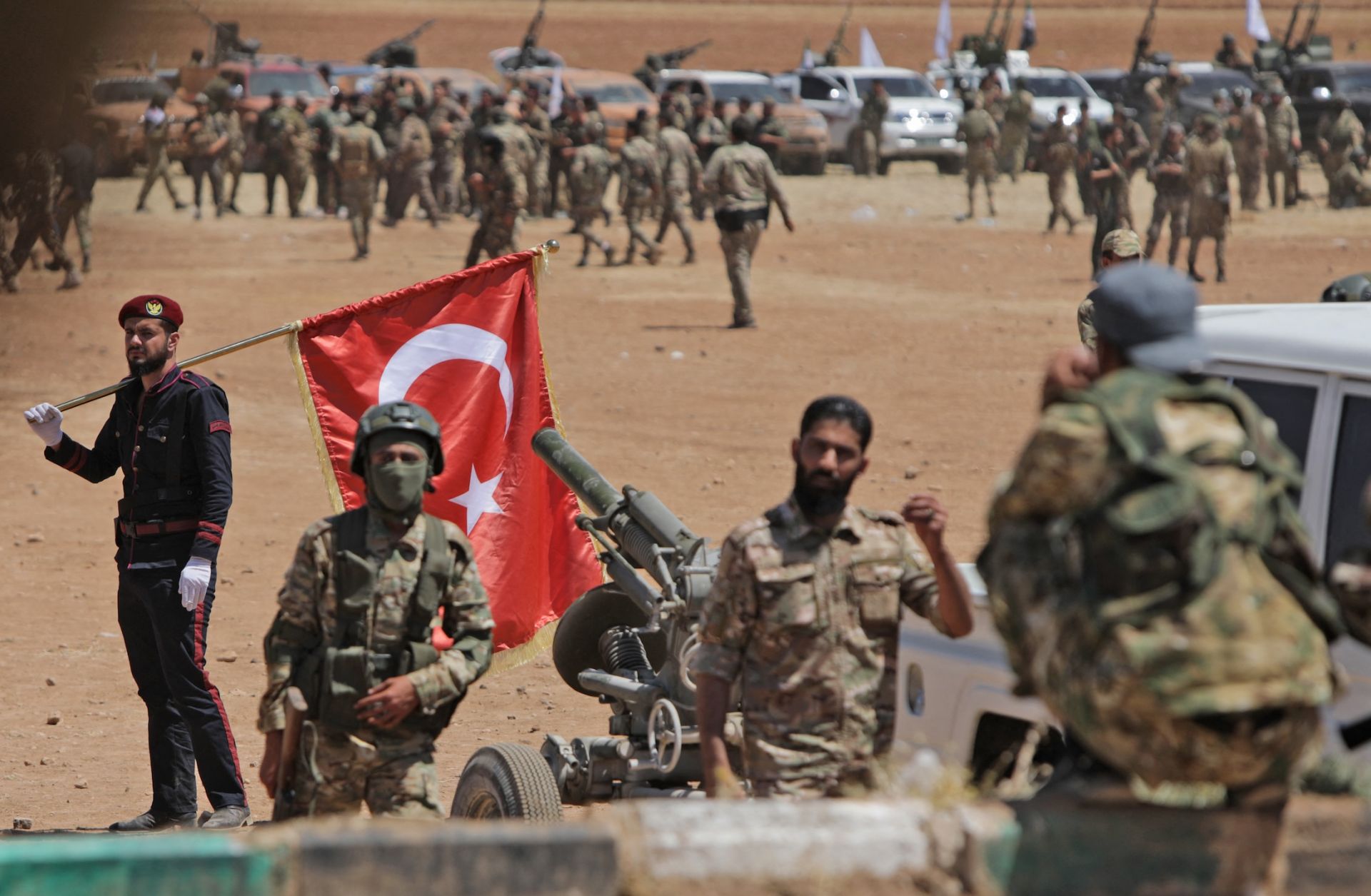A man carries a Turkish national flag as Turkey-backed Syrian fighters gather along the frontlines opposite Kurdish forces near the town of Dadat in Syria's northern Aleppo province, on July 5, 2022. 