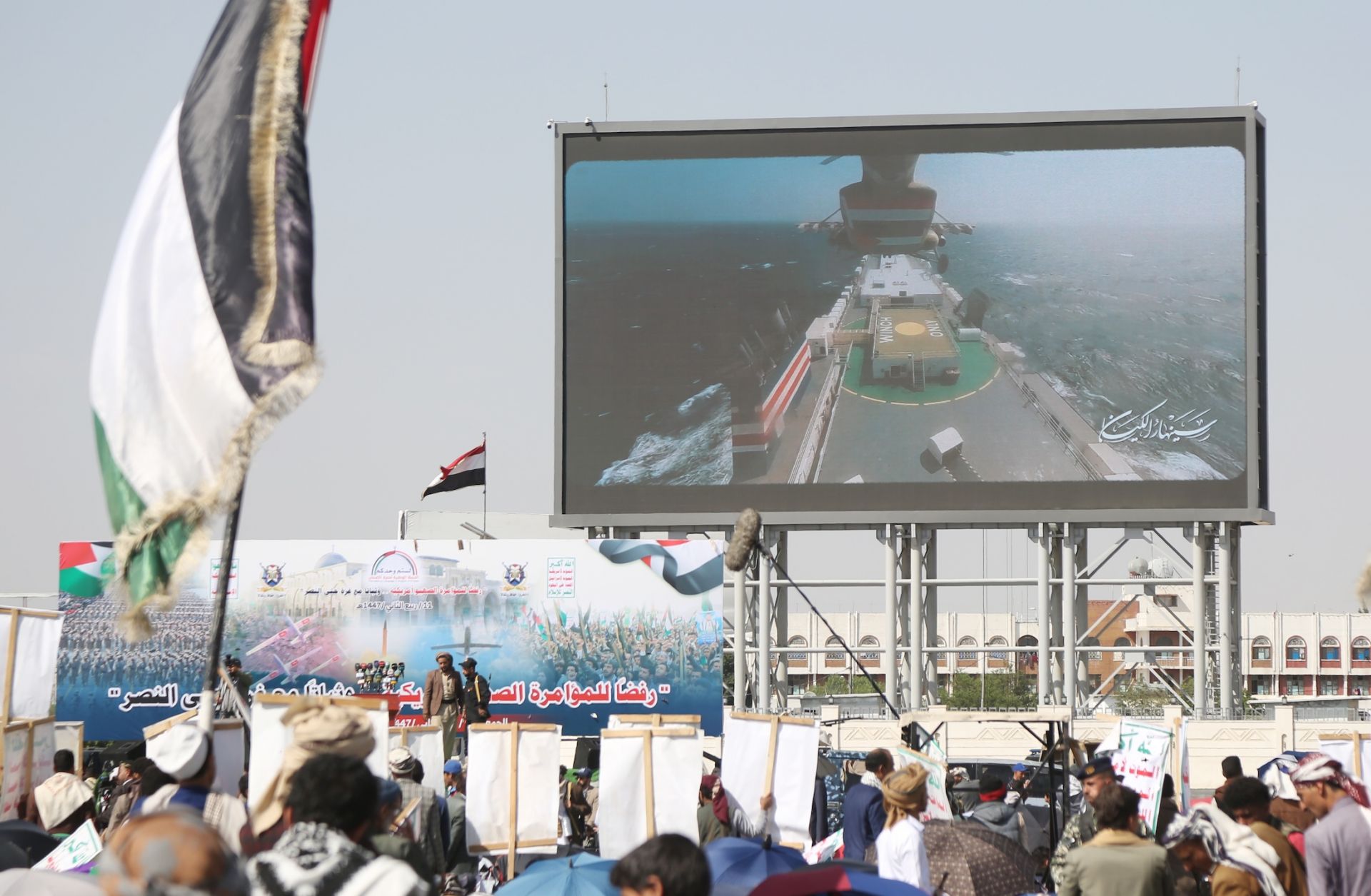 Yemenis stand under a billboard depicting the seizure of an Israeli-linked ship in the sea by Yemen's Houthi-run coast guards during a demonstration staged in solidarity with the people of Gaza and against U.S. President Donald Trump's deal to end the Israel-Hamas war on Oct. 3, 2025, in Sanaa, Yemen. 