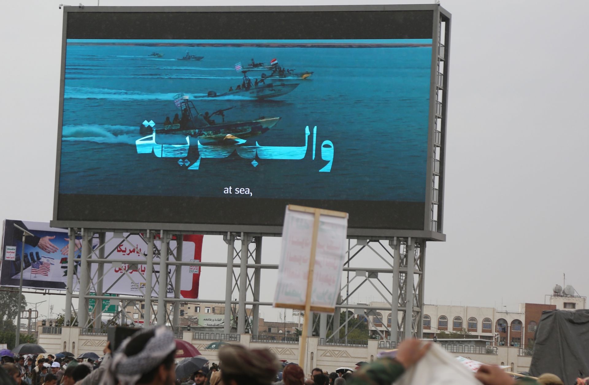 People in Sanaa, Yemen, stand under a large screen broadcasting Houthi-run coastguard forces patrolling in the Red Sea on March 13, 2026. People in Sanaa, Yemen, stand under a large screen broadcasting Houthi-run coastguard forces patrolling in the Red Sea on March 13, 2026.