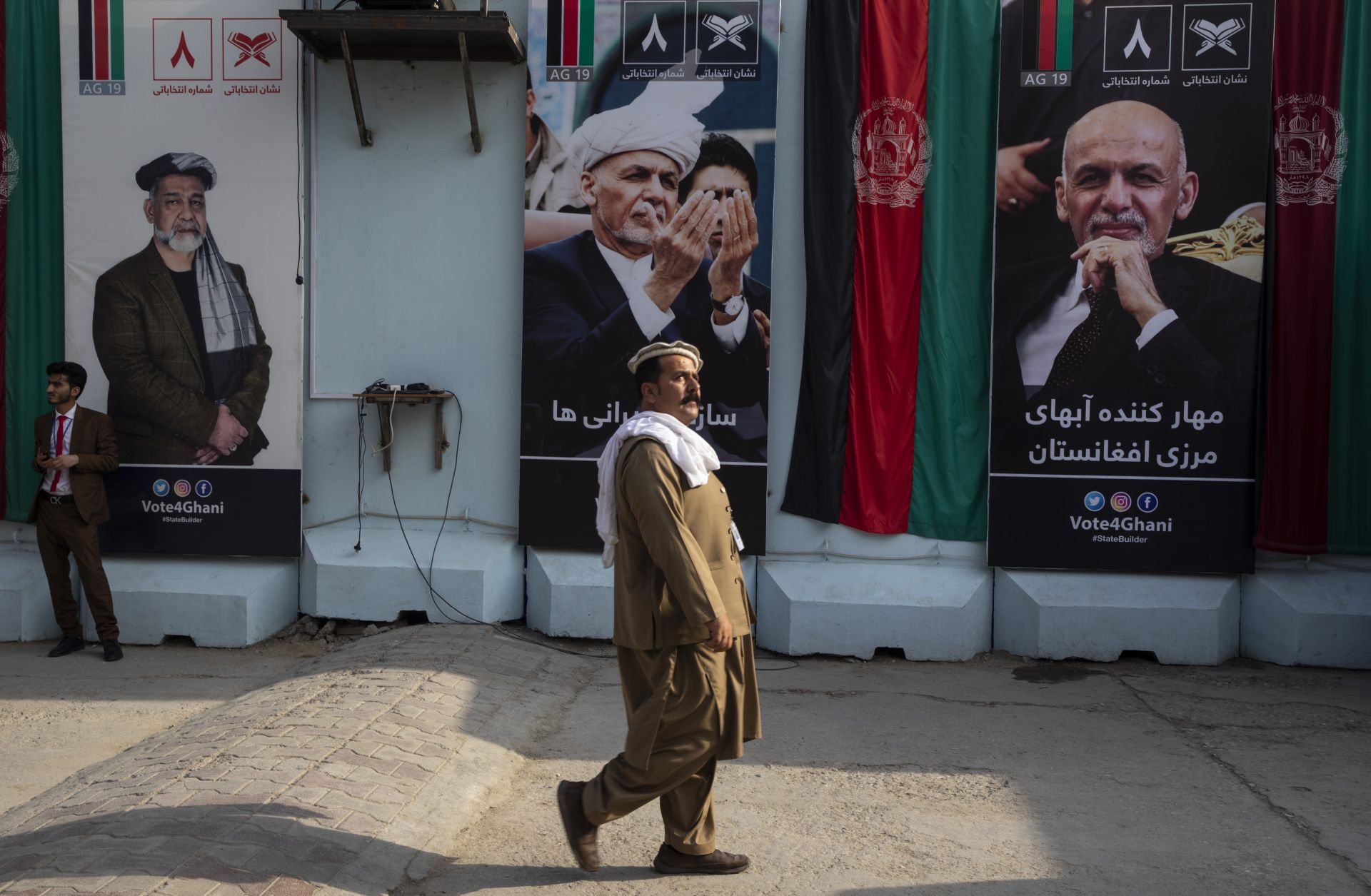 A man walks by election billboards outside of Afghan President Ashraf Ghani's campaign headquarters in Kabul on Sept. 29.