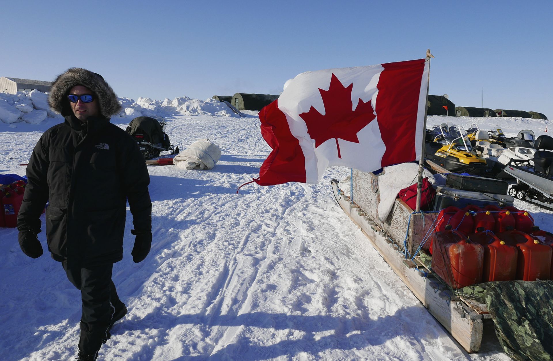 A project manager for the Arctic Research Foundation on April 9, 2015, walks past snowmobiles used by Canadian troops deployed to the territory of Nunavut to demonstrate Canadian sovereignty in the Arctic.