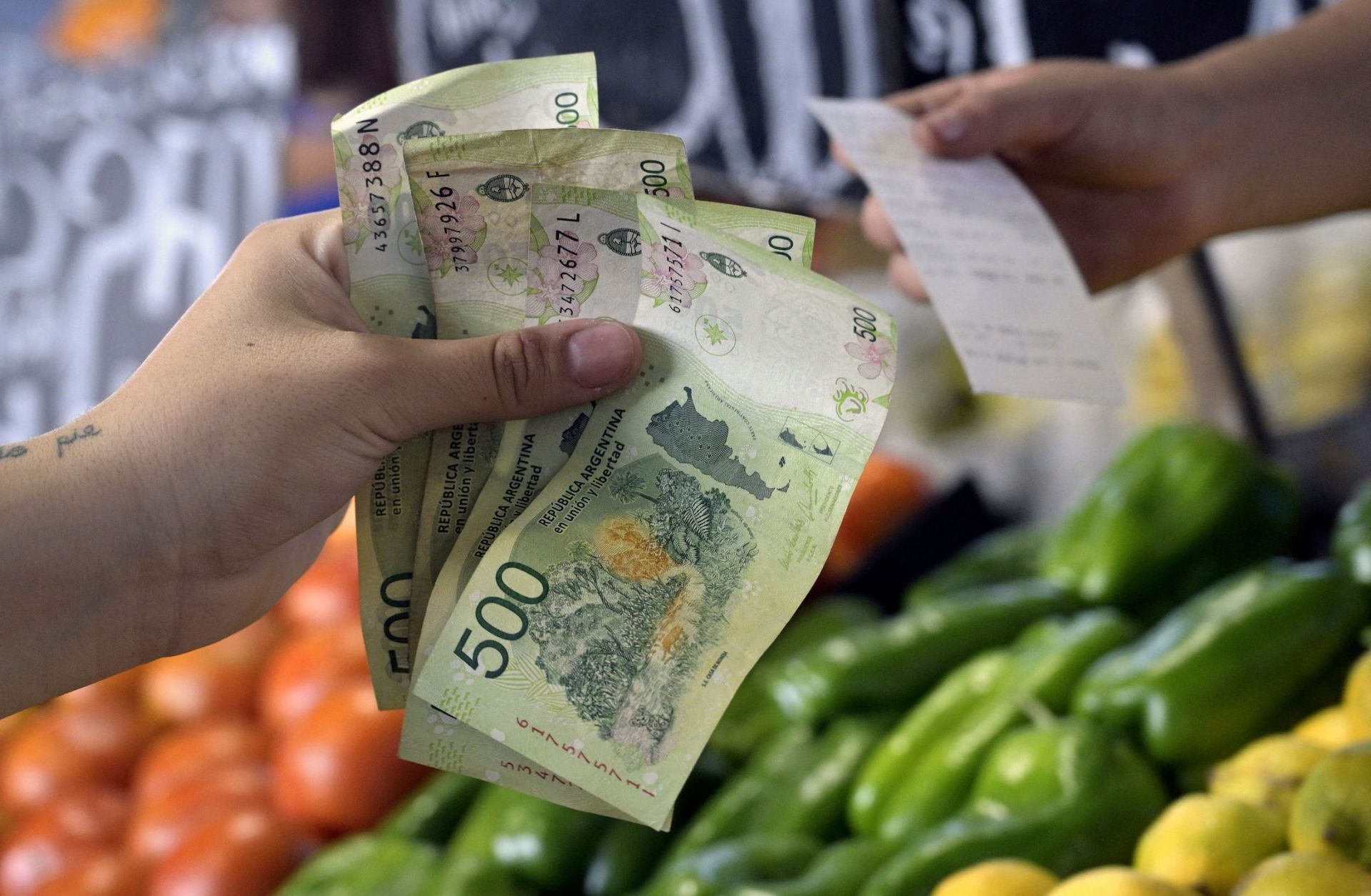A woman pays for fruits and vegetables in Argentine pesos at a market in Buenos Aires on Feb. 10, 2023.