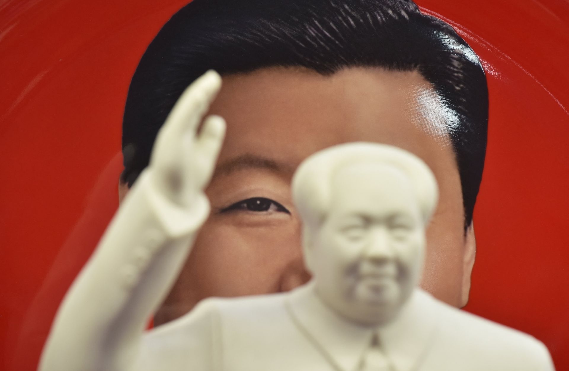 A decorative plate featuring an image of Chinese President Xi Jinping is seen behind a statue of late communist leader Mao Zedong at a souvenir store next to Tiananmen Square in Beijing, China, on Feb. 27, 2018. 