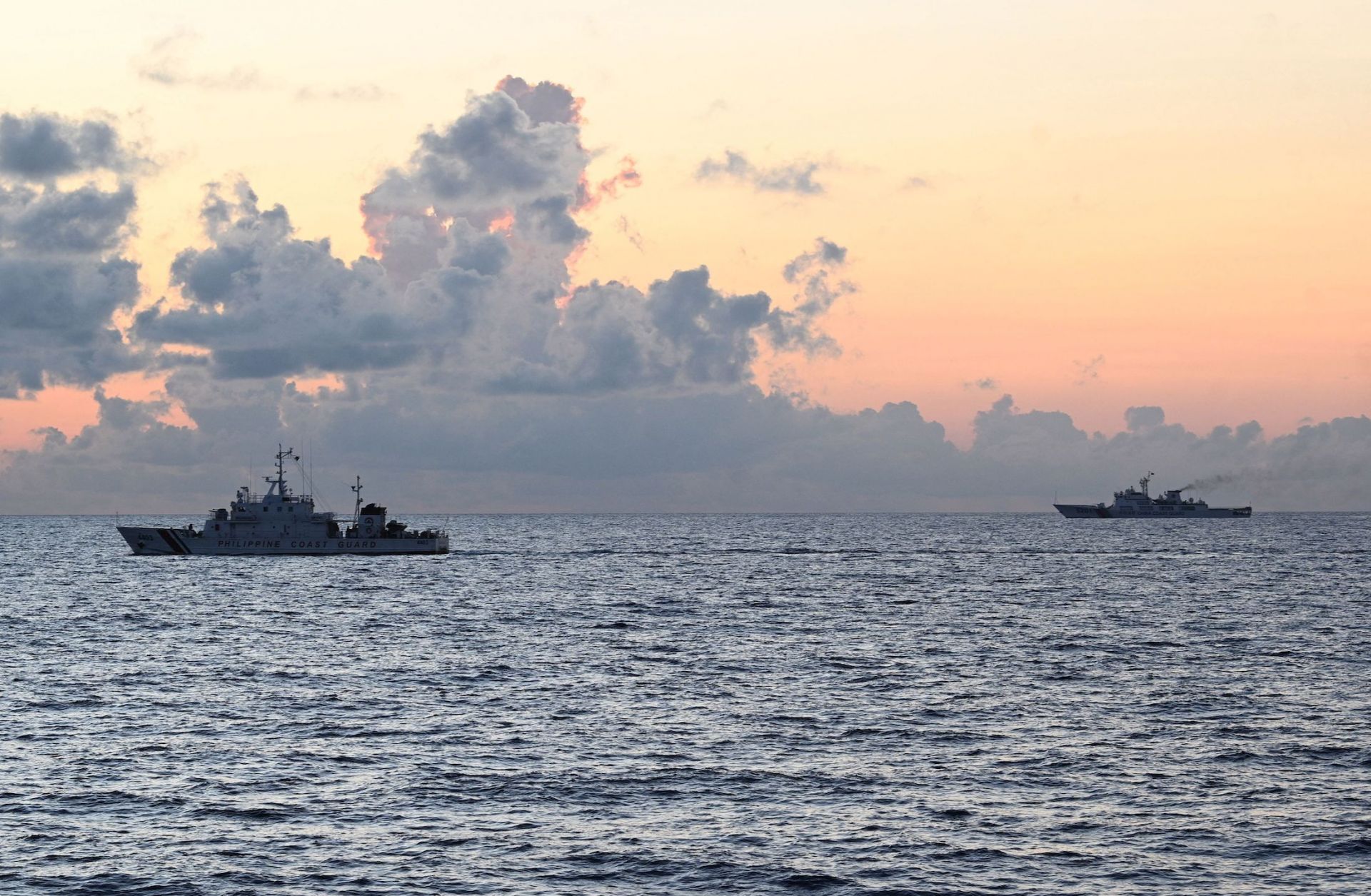 A Chinese coast guard ship (R) shadows the Philippine coast guard vessel BRP Malapascua (L) while on patrol at the Second Thomas Shoal in the Spratly Islands in the disputed South China Sea on April 23, 2023.