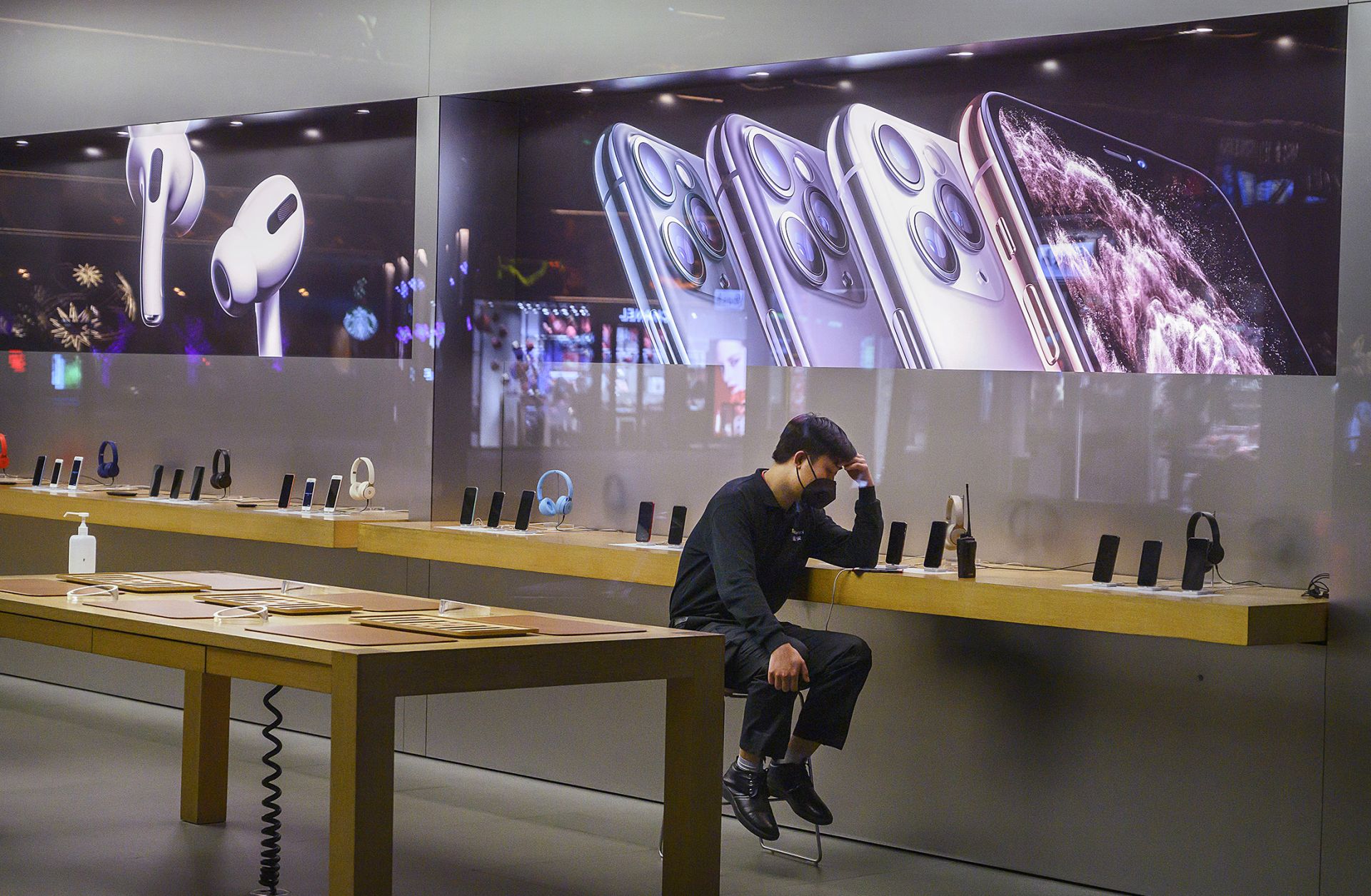 An employee sits in the showroom of an Apple store in Beijing after it closed for the day on Feb. 1, 2020.