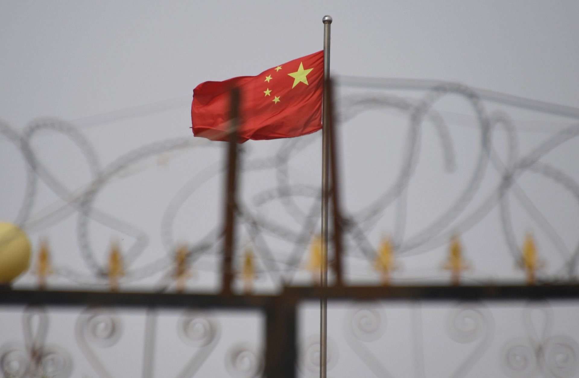 The Chinese flag behind razor wire.