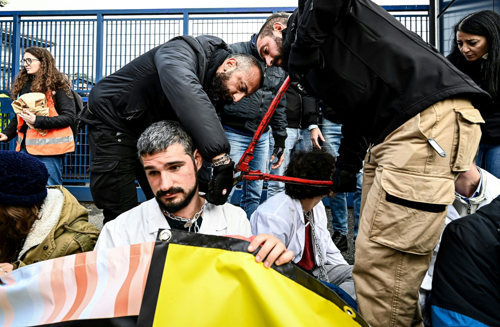 Police officers remove a chain Nov. 10, 2022, from the neck of an activist as climate activists block the entrance of the Milano Linate Prime fixed-base operator airport facility in Milan.