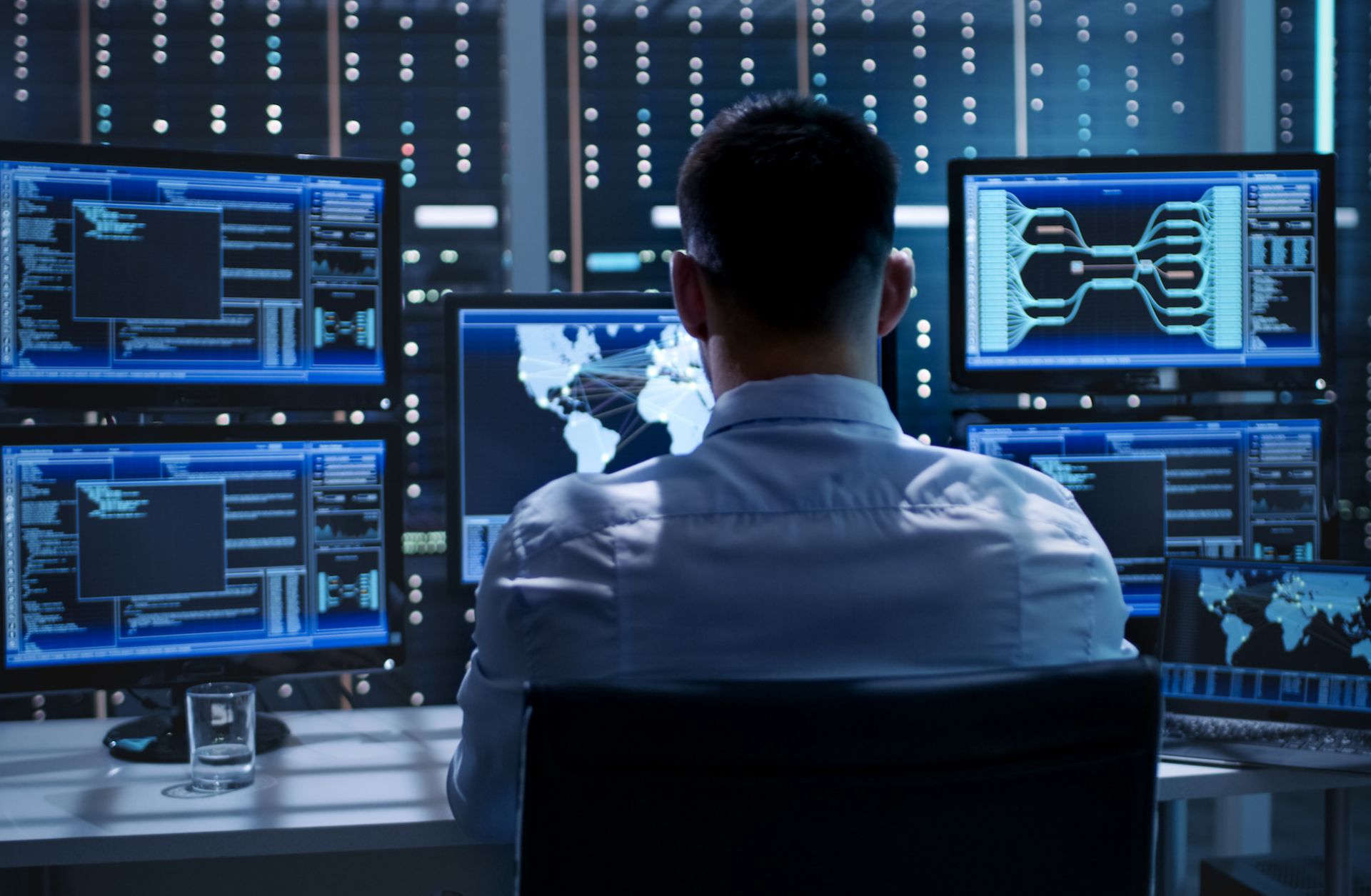 A man monitors computer screens. 