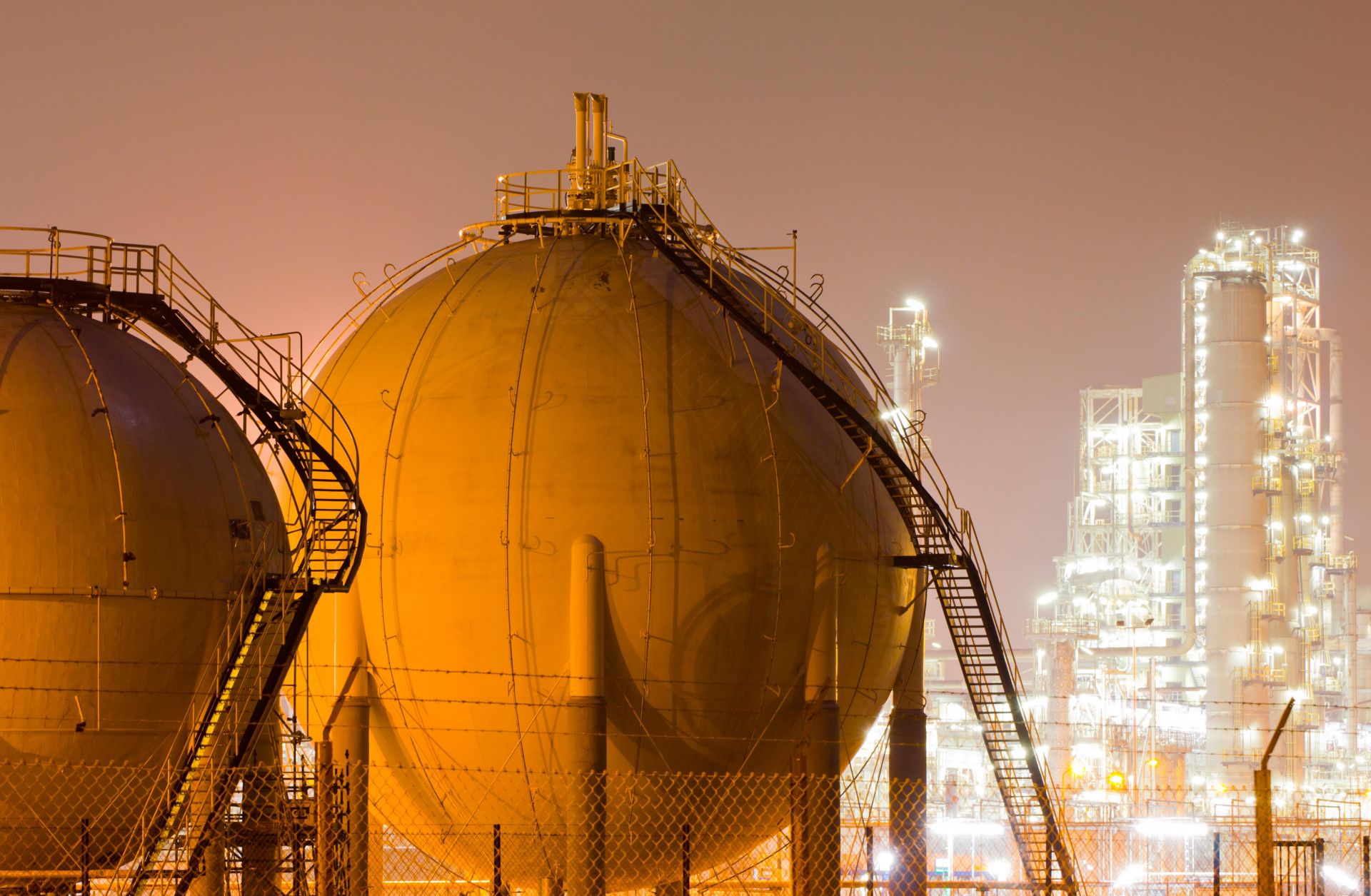 Storage tanks for liquefied natural gas sit in a large oil-refinery plant