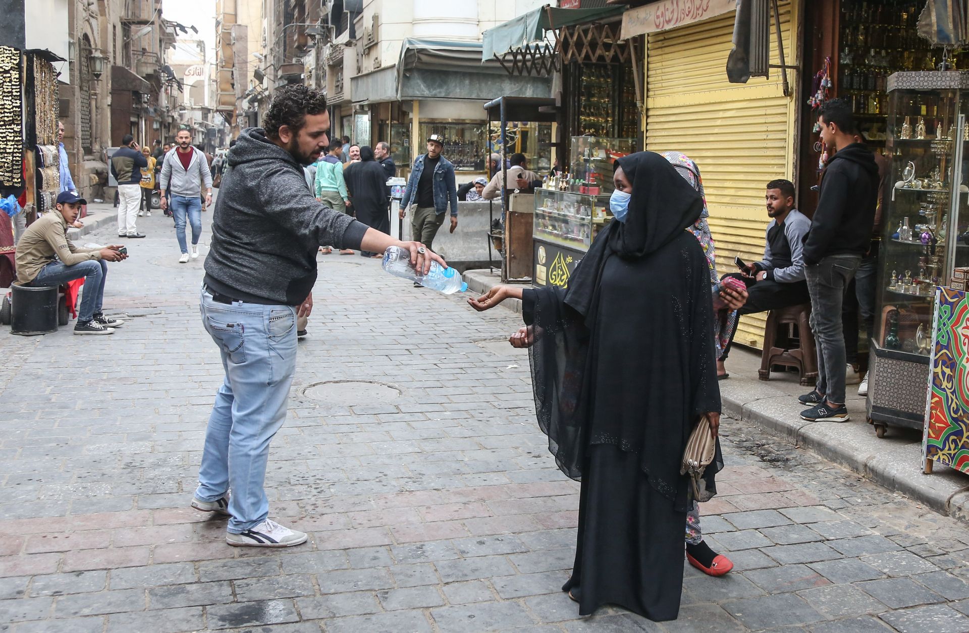 A man provides a pedestrian with hand sanitizer as protection against COVID-19 on the historic Al-Moez street in Cairo, Egypt, on March 23, 2020.