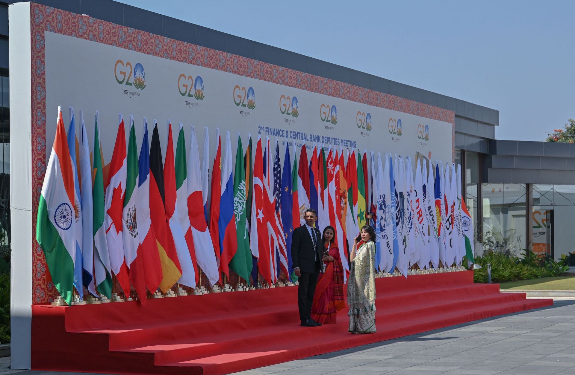 Officials stand near flags of participating countries and organizations at the venue where the second meeting of the G-20 Finance and Central Bank Deputies under India's G-20 presidency has begun Feb. 22, 2023, in Bengaluru, India.