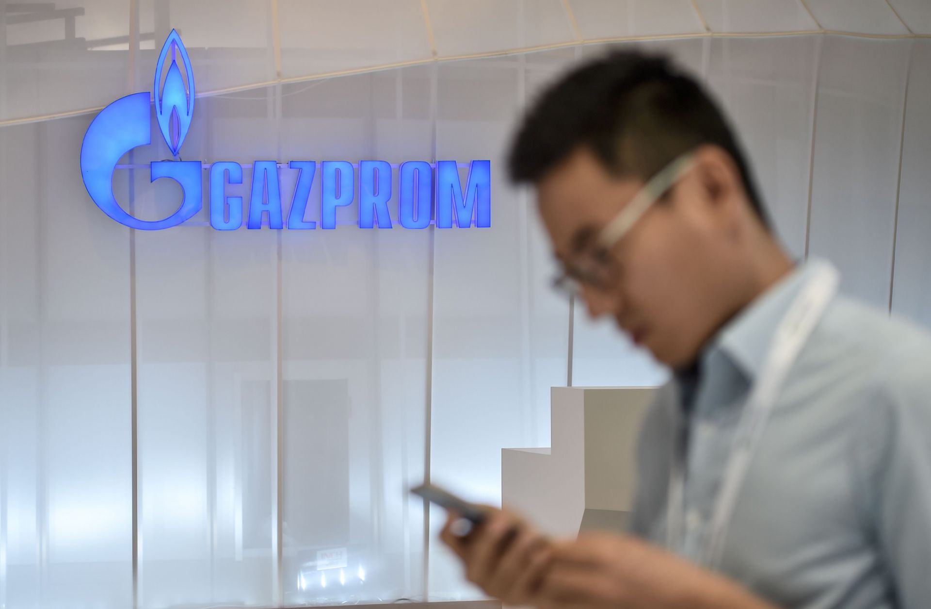 A man looks at his mobile phone as he walks past a Russian Gazprom stand in Istanbul. 