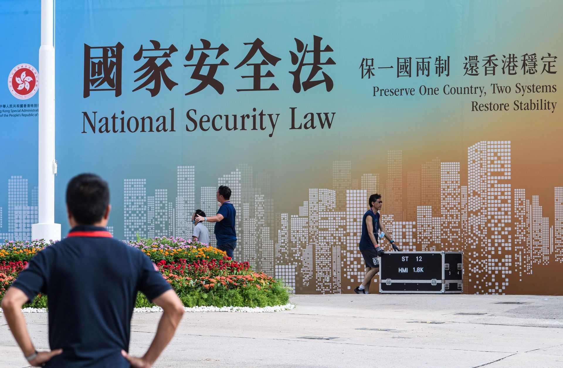 Technicians in Hong Kong walk next to a banner supporting China’s new national security law following a flag-raising ceremony marking the 23rd anniversary of the city’s British handover on July 1, 2020. 