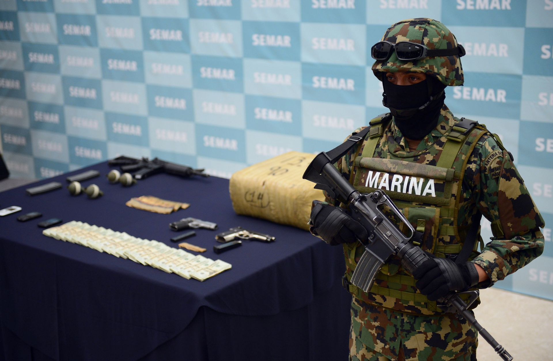 A soldier guards firearms, hand grenades and other illegal items seized from the Zeta drug cartel.
