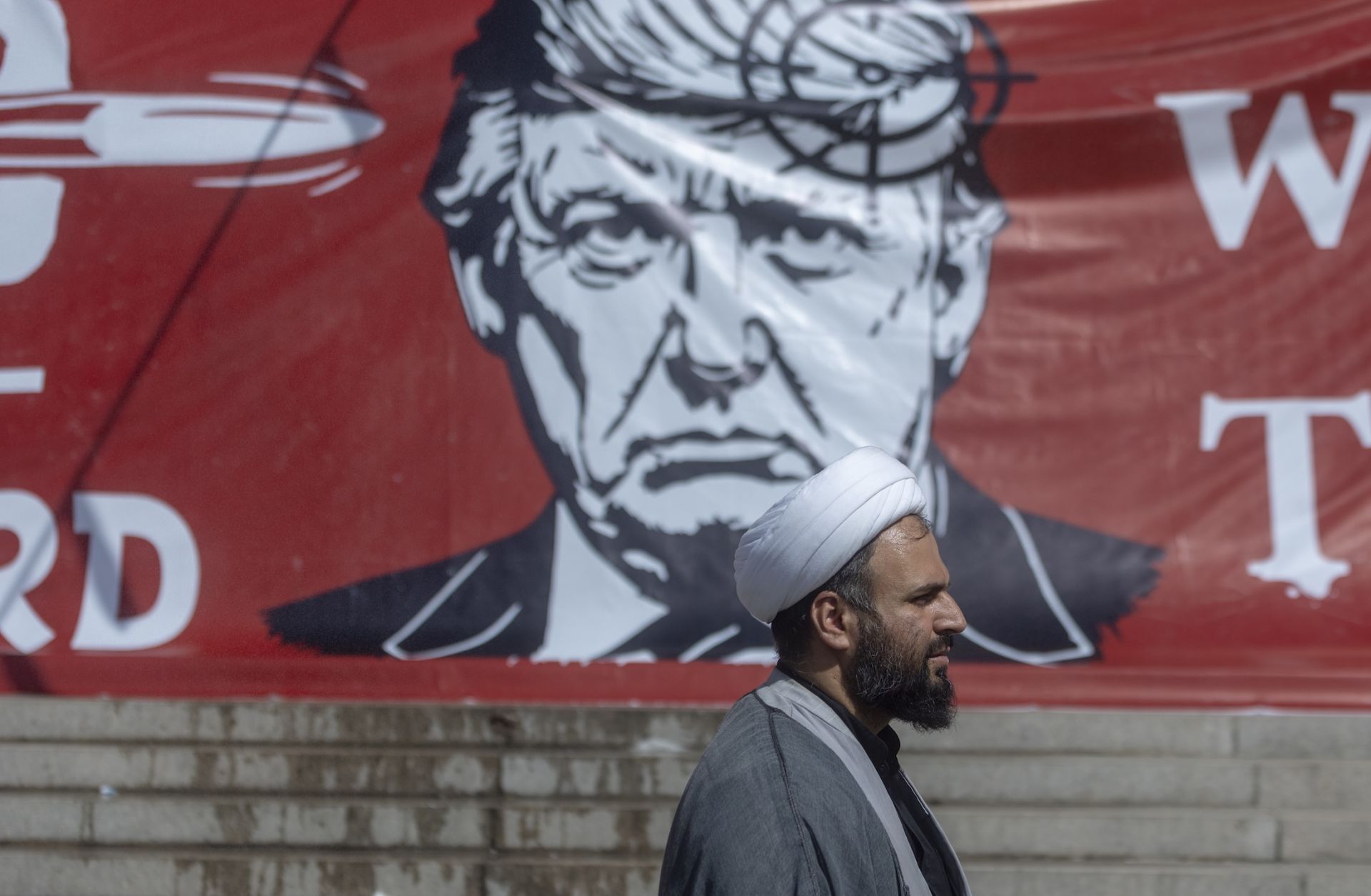People pass a large banner depicting U.S. President Donald Trump with a target on his head, during funeral ceremonies for Iran's slain Supreme Leader, Ayatollah Ali Khamenei, at the Grand Mosalla on July 5 in Tehran, Iran. 