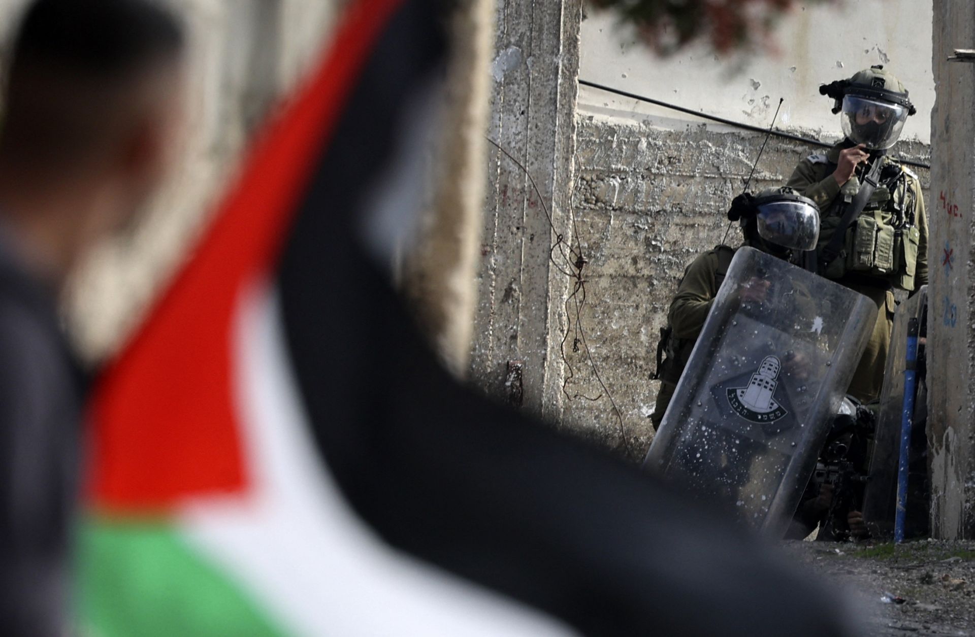 A Palestinian demonstrator waves a flag during confrontations with Israeli troops Jan. 6, 2023, in the West Bank village of Kfar Qaddum, near the Jewish settlement of Kedumim.