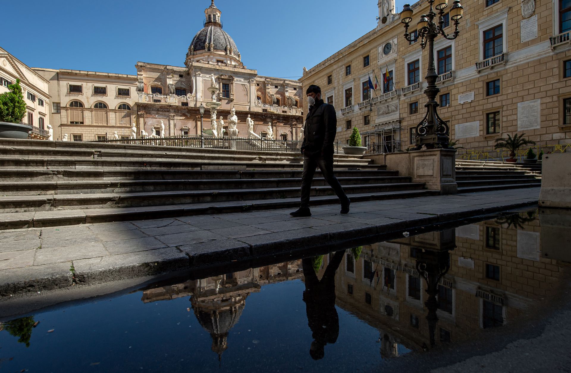 A man wearing a face mask walks in Pretoria square in Palermo, Italy, on March 11, 2020.
