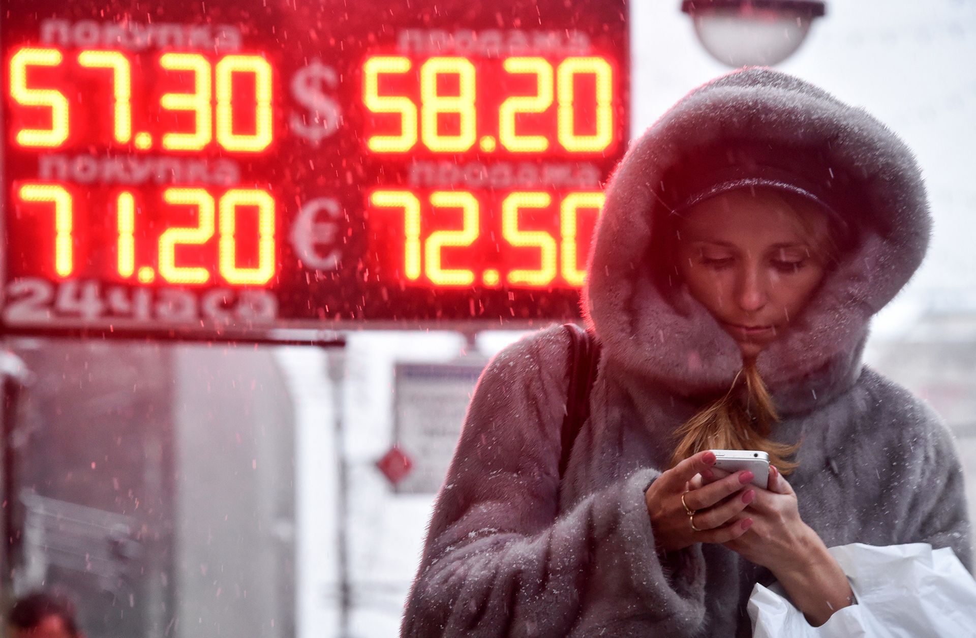 A woman in Moscow walks past a sign showing the Russian ruble's value compared the the U.S. dollar and euro.