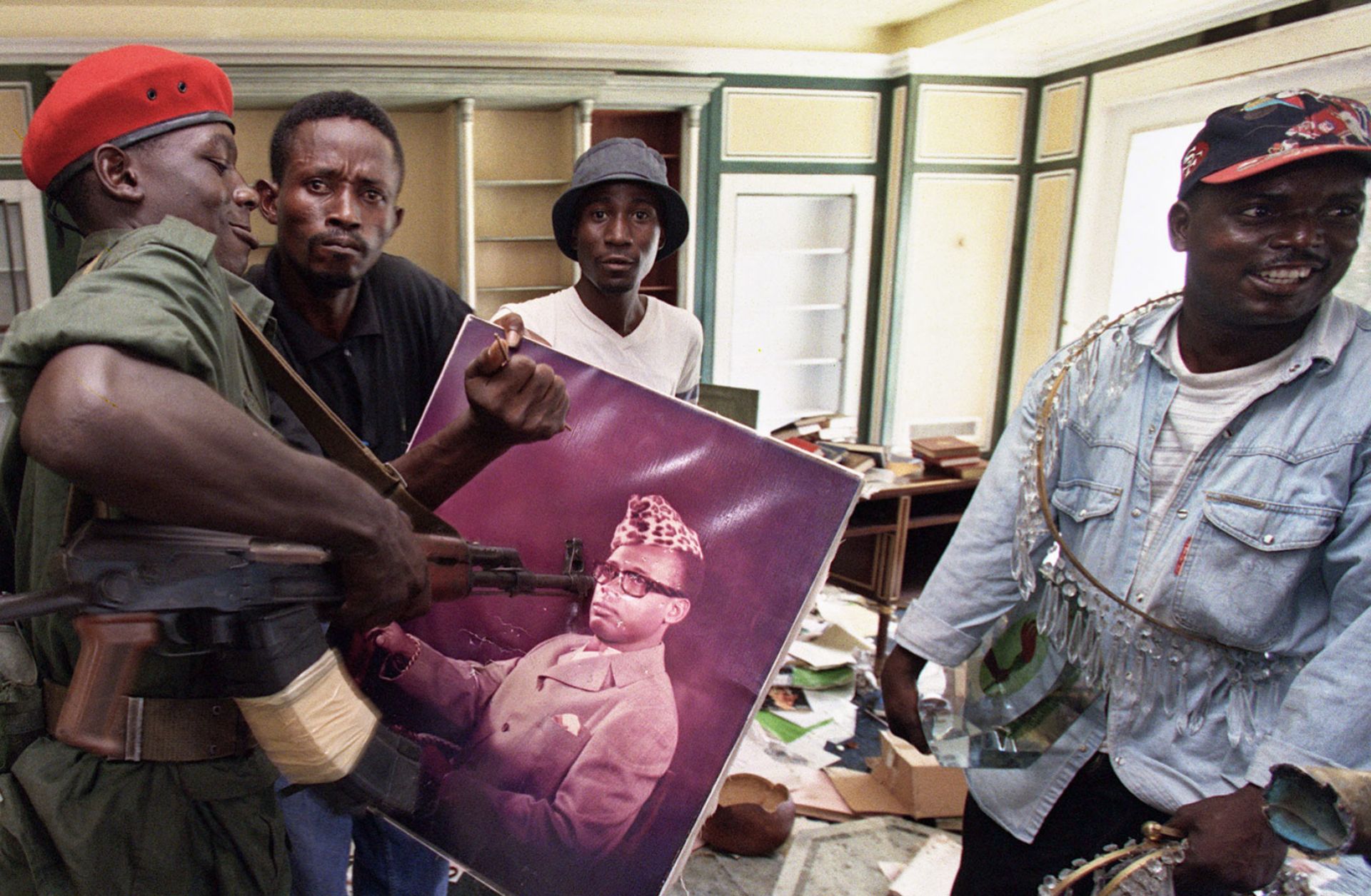 A Congolese rebel alliance soldier surrounded by looters in Kinshasa prods a photograph of ousted Zairean President Mobutu Sese Seko in 1997. African populations are demanding more from their leaders, and not all leaders are prepared to give it.