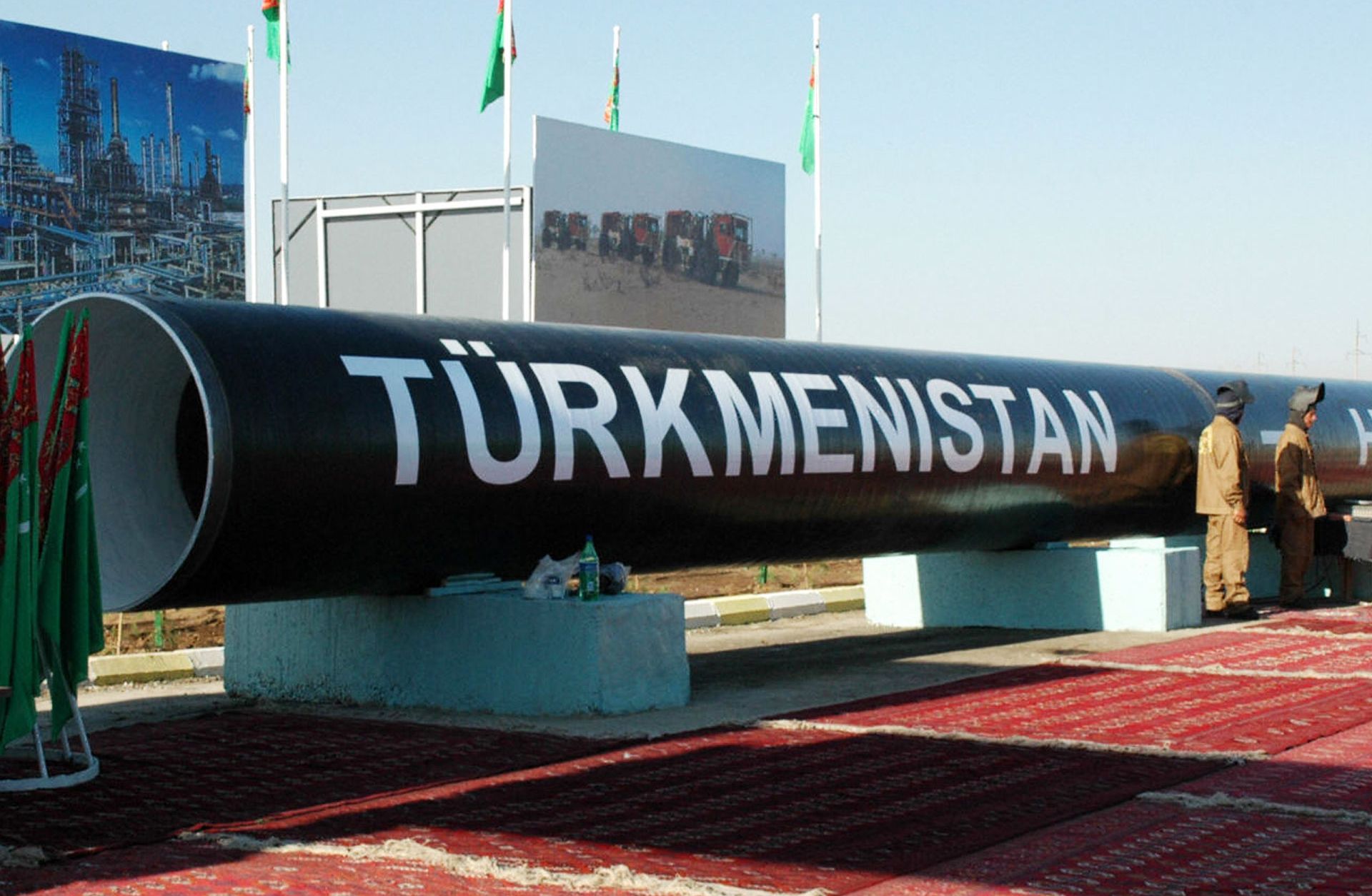 Two workmen stand next to the symbolic first piece of a natural gas pipeline to China outside of Turkmenabat in 2007.