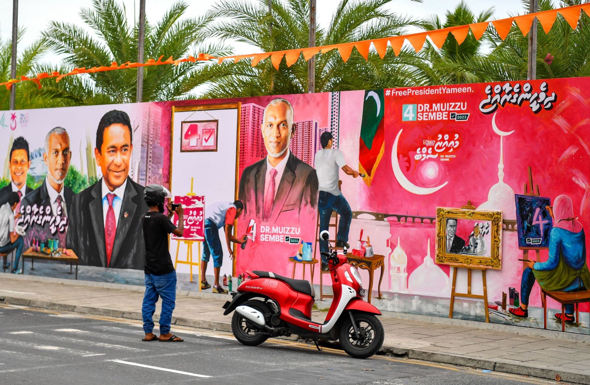  A commuter in Male, the Maldives, takes pictures of a decorated wall along a street ahead of the country's presidential election on Sept. 6, 2023.