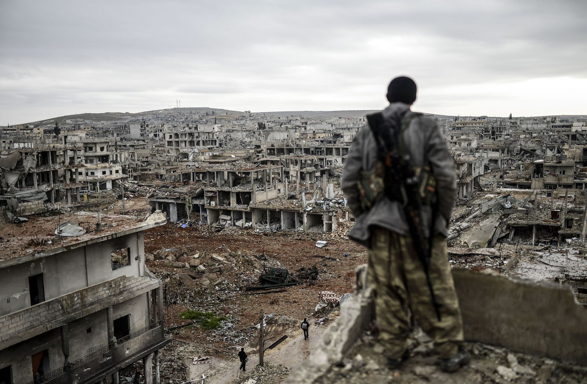 A man stands on top of a building overlooking the destryoed town of Kobane, Syria.