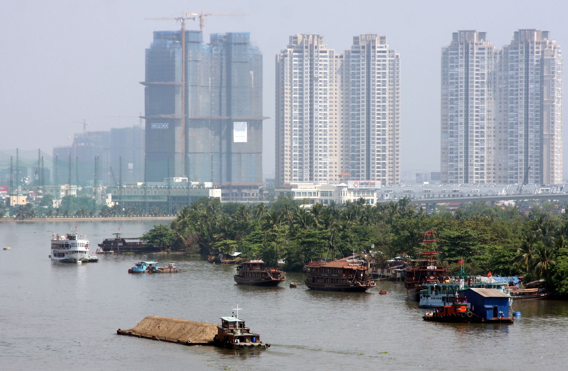 New buildings tower above boats on the Saigon river.
