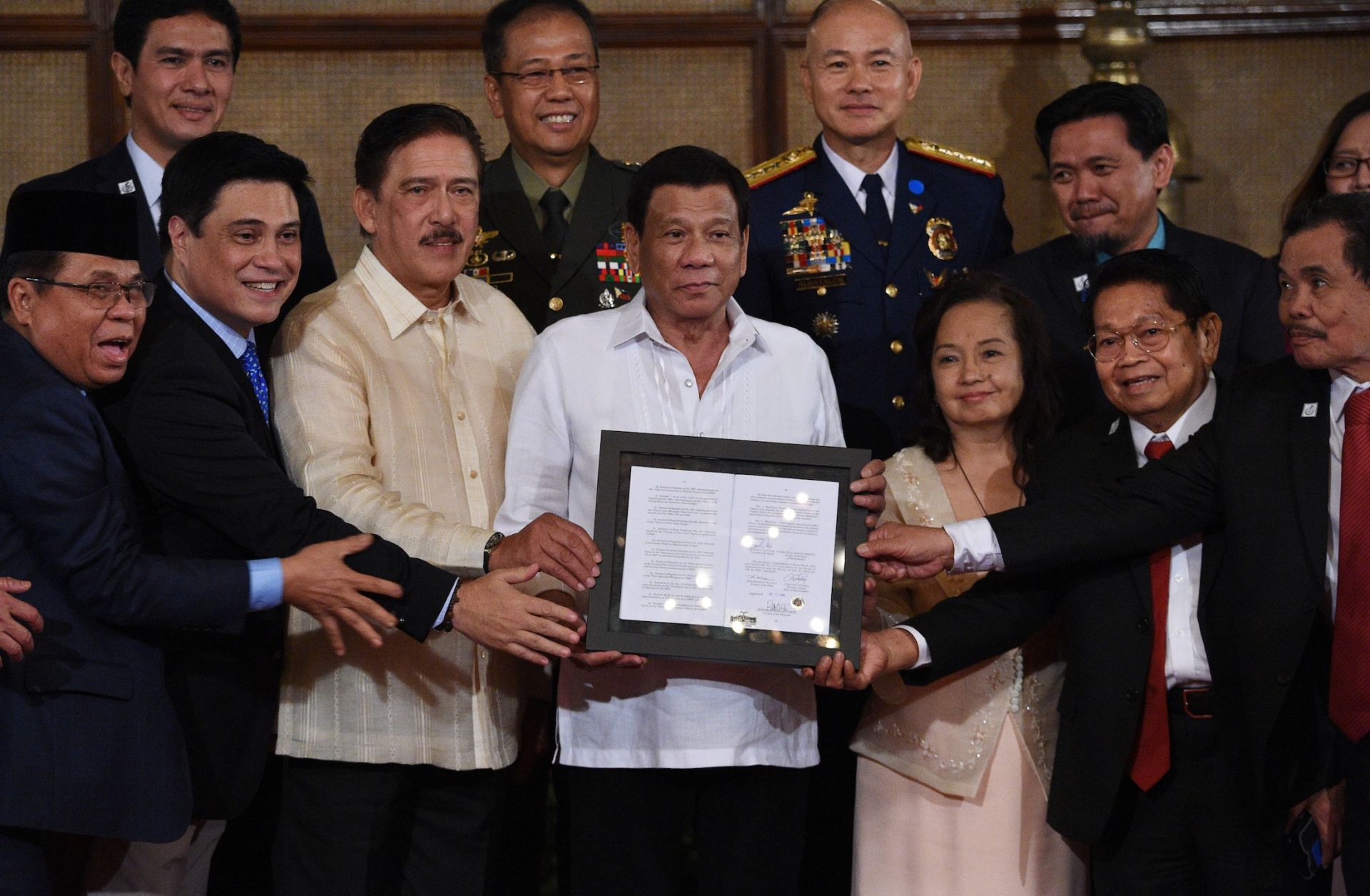 Philippine President Rodrigo Duterte, center, poses with lawmakers, leaders of the Moro Islamic Liberation Front and military and police officials during a presentation ceremony for the new Bangsamoro law in Manila on Aug. 6, 2018.