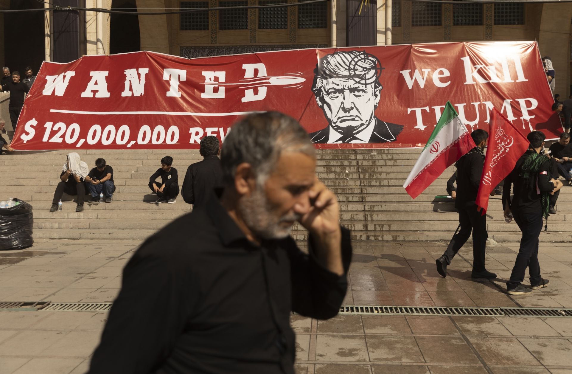 People pass a large banner depicting U.S. President Donald Trump with a target on his head during funeral ceremonies for Supreme Leade, Ayatollah Ali Khamenei on July 5 in Tehran, Iran. U.S.-Iran clashes will likely continue over the next week.