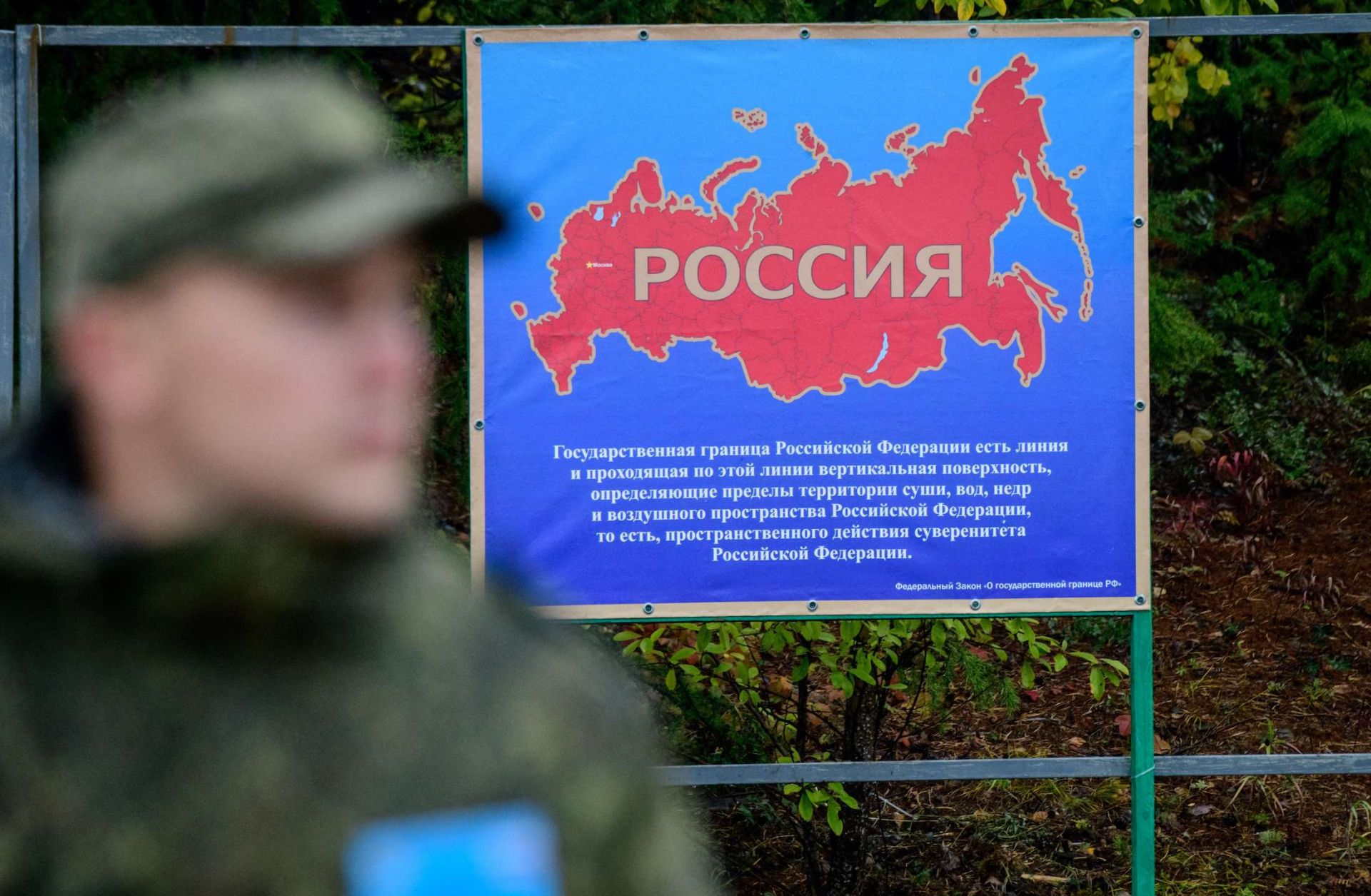 A Russian soldier stands next to a poster showing a map of Russia during military drills in Siberia. 