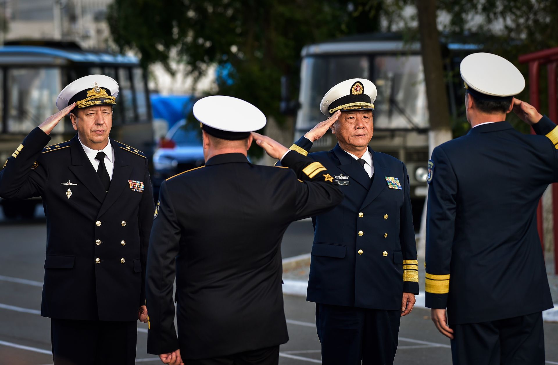 Military officials salute each other in a ceremony before Russia and China warships set out for a naval cooperation exercise.