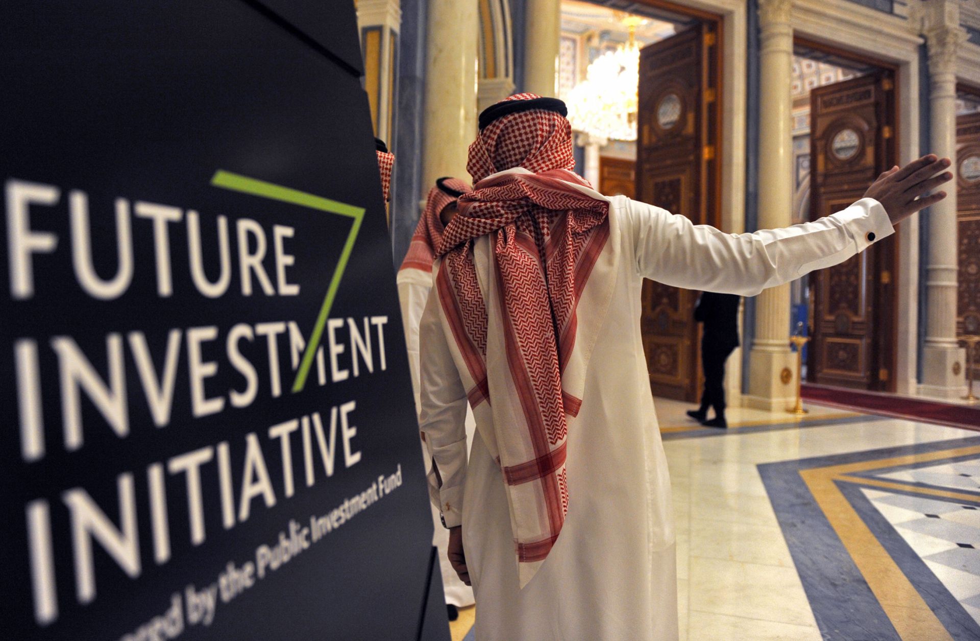 A Saudi man gestures near a sign at the start of the three-day Future Investment Initiative in Riyadh on Oct. 23, 2018.