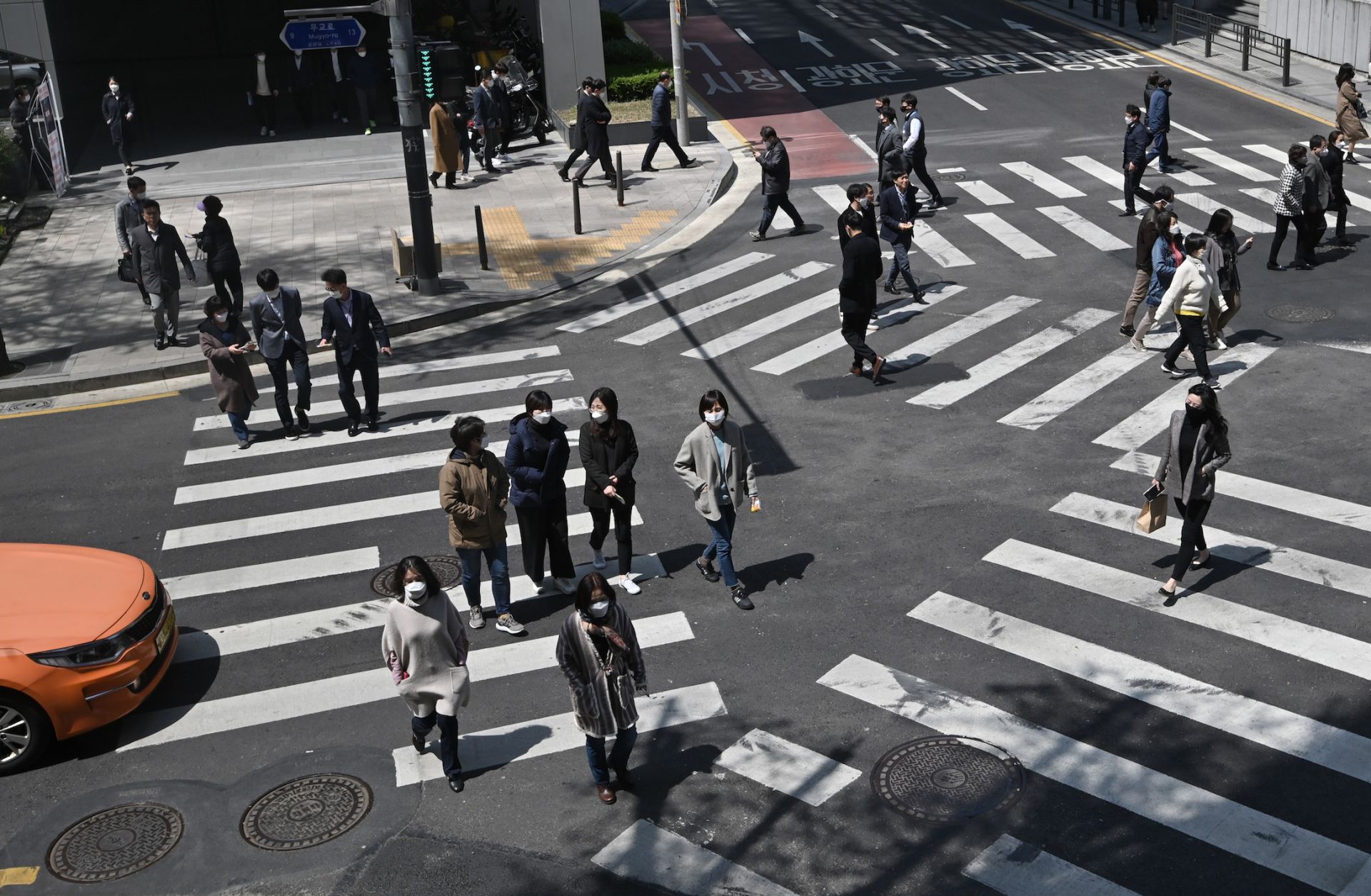 Pedestrians wearing face masks cross an intersection in Seoul, South Korea, on April 23, 2020. In the first quarter of 2020, South Korea's economy saw its worst performance in more than a decade as COVID-19 spread across the country. 