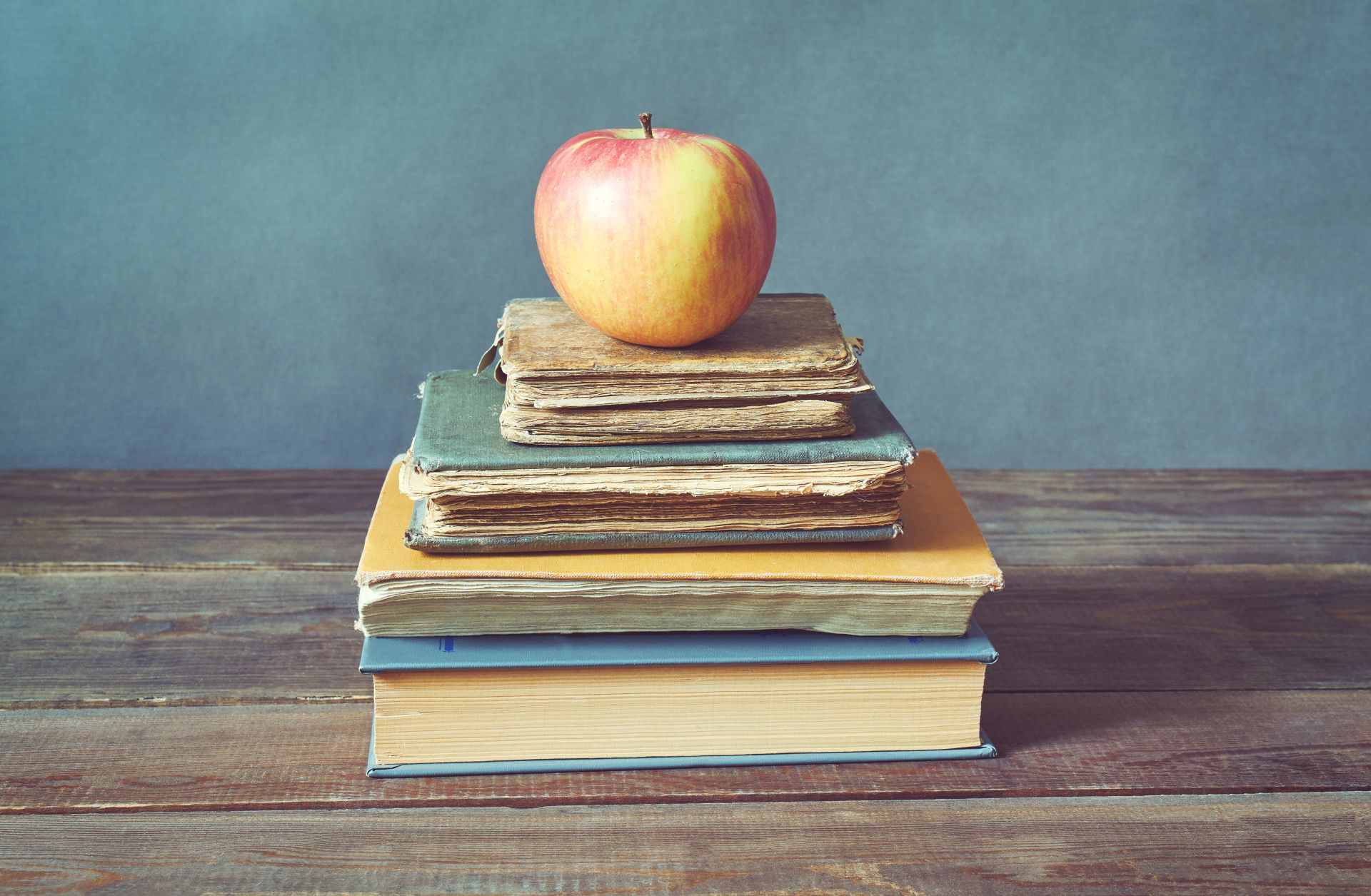 An apple sits atop a stack of books.