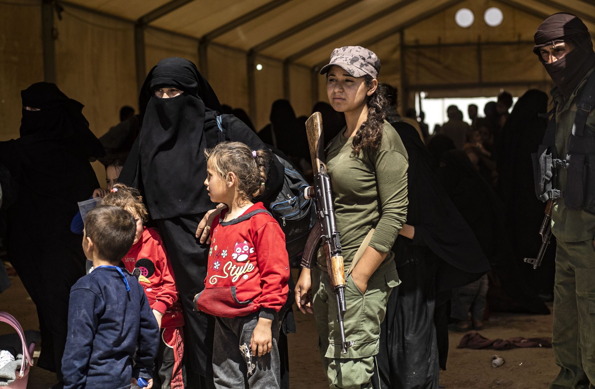 Fighters with the U.S.-backed, Kurdish-led Syrian Democratic Forces guard women and children waiting to leave the al-Hol camp in northeastern Syria on June 3, 2019.