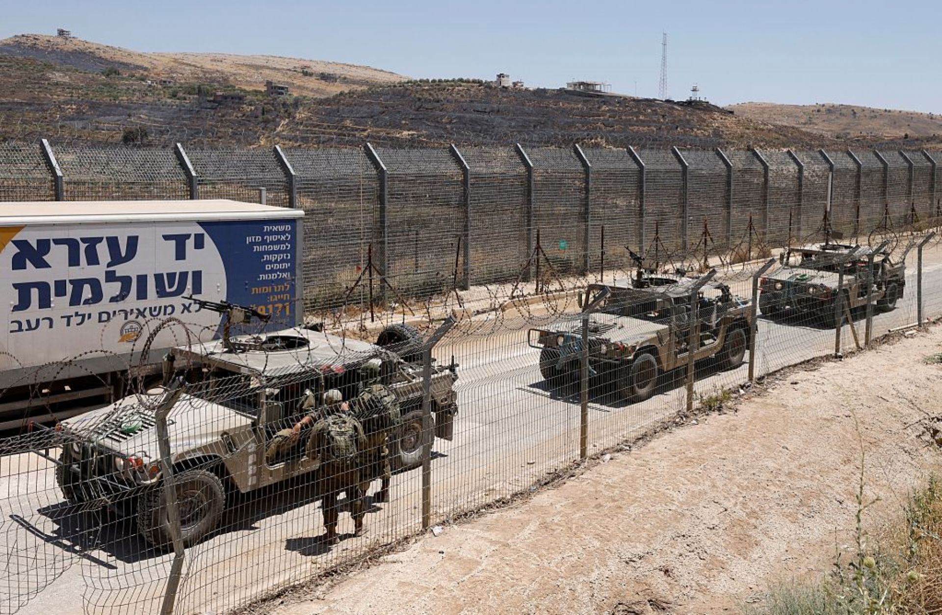 Israeli military vehicles drive along the border fence into Israel, near the town of Majdal Shams, in the Israeli-annexed Golan Heights, on July 17, 2025.