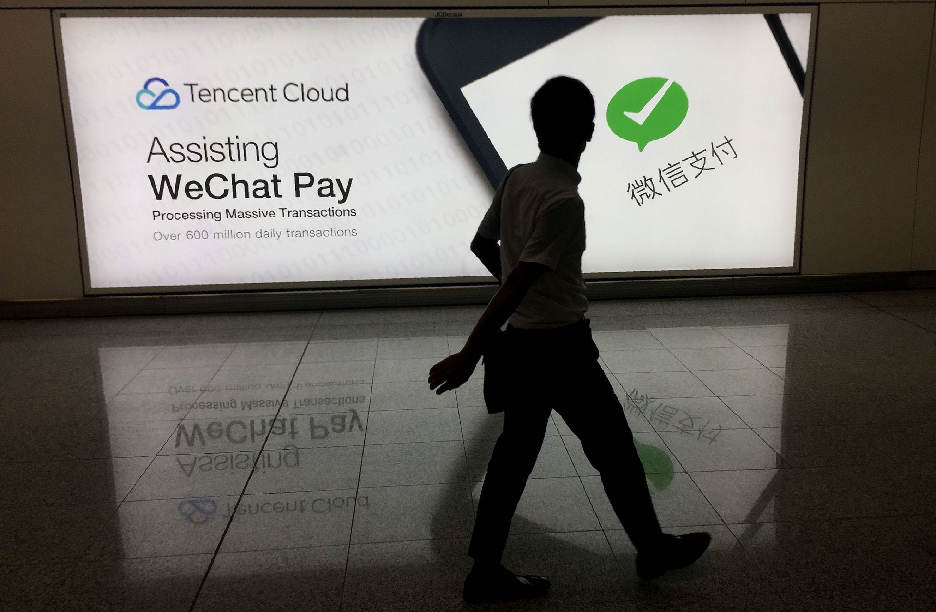 The social media platform WeChat is owned by China's Tencent, which is competing with rivals Alibaba and Baidu for control of the Chinese internet market. In this August 2017 photo, a man walks past an ad in Hong Kong's international airport for the social media platform WeChat, which is owned by China's Tencent.