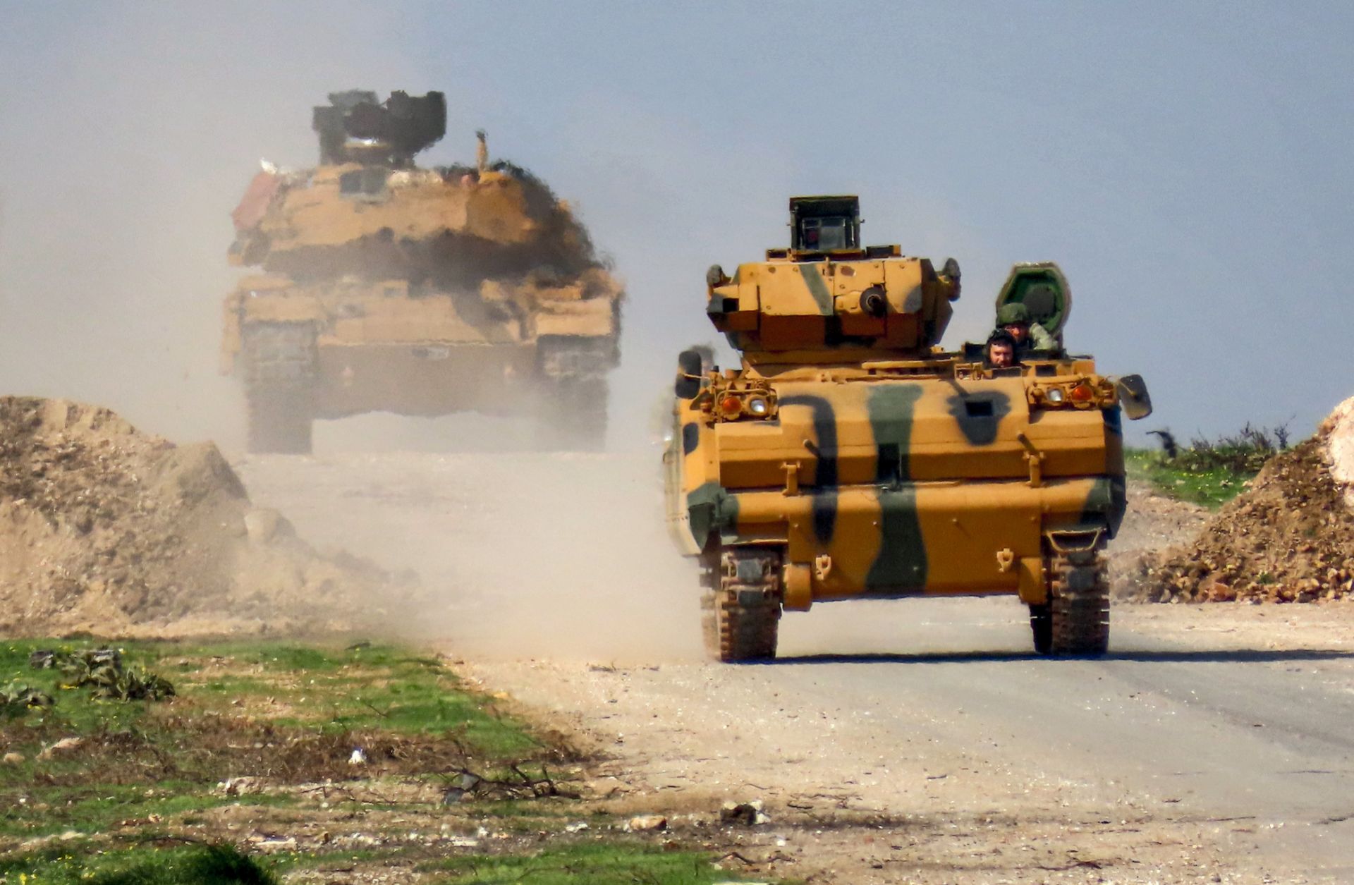 A Turkish military infantry fighting vehicle (IFV), followed by a battle tank, is seen along the M4 highway in northern Syria on March 15, 2020.