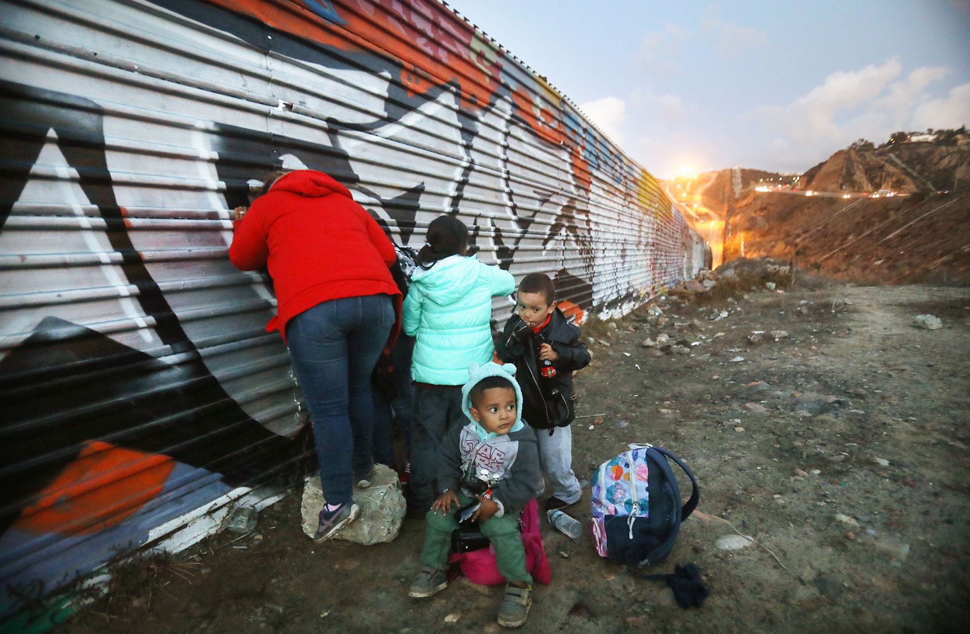 A picture showing Honduran migrants gathering on the Mexican side of the U.S.-Mexico border fence near Tijuana after unsuccessfully attempting to cross into the United States, Dec 1. 