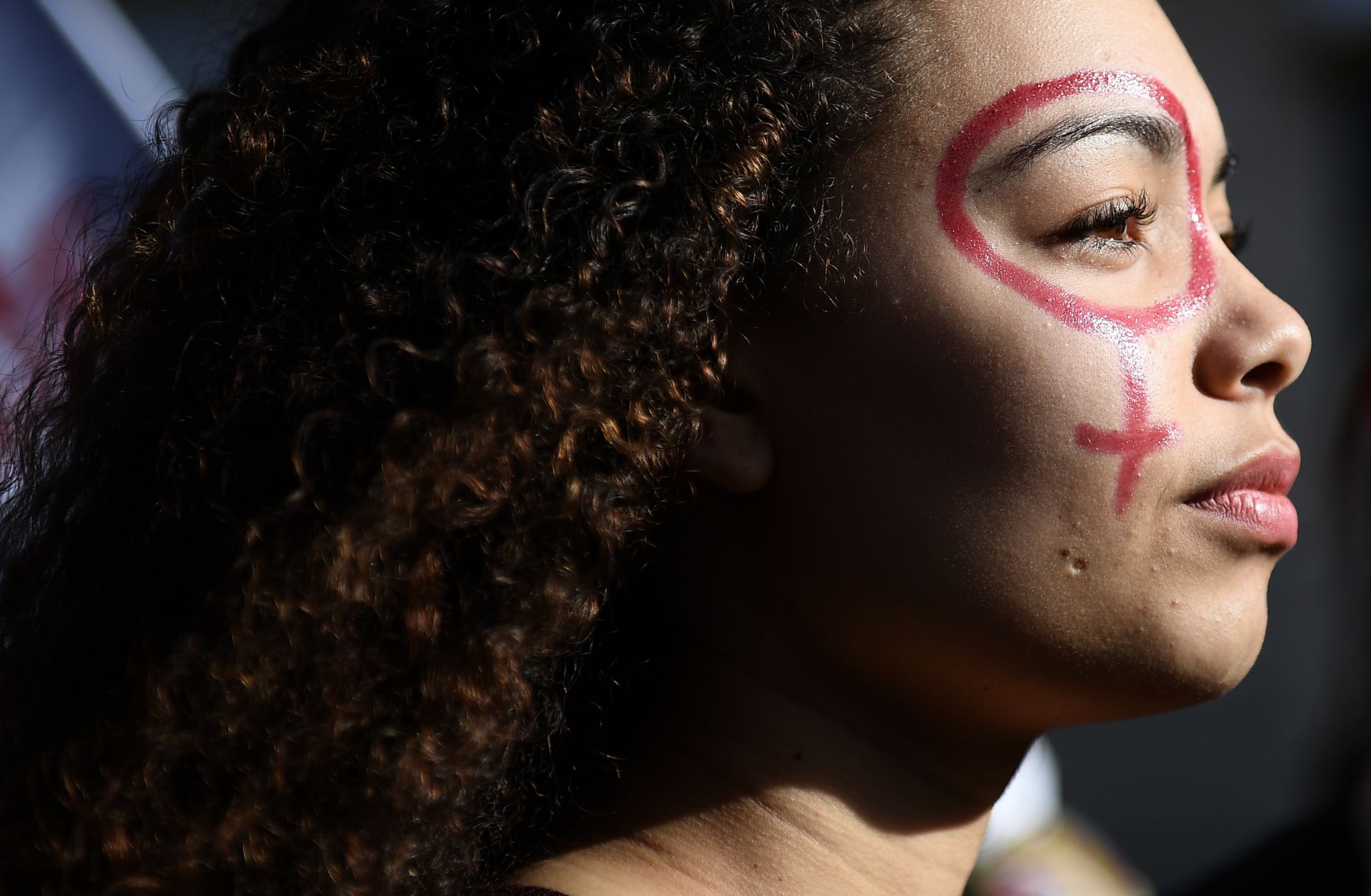 A woman with the female gender pictogram made up on her face attends a demonstration as part of the 40th International Women's Day on March 8, 2017 in Marseille.