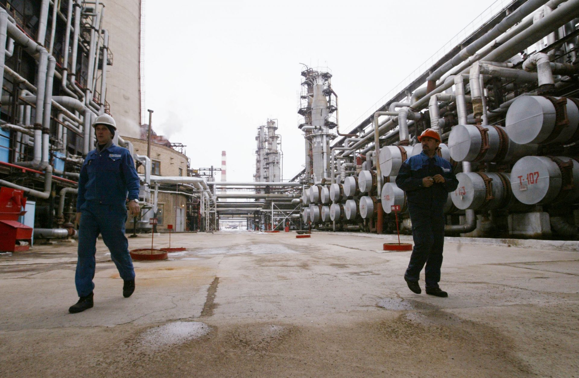 Workers walk through an oil refinery.