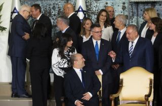 Israeli Prime Minster Naftali Bennett (bottom center) talks with members of his new coalition government before posing for a group photo at the President's Residence in Jerusalem on June 14, 2021. 