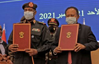 Sudan’s military chief (left) and prime minister show documents during a deal-signing ceremony in Khartoum on Nov. 21, 2021. 