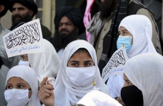 Schoolgirls hold Taliban flags during a ceremony to mark the start of the academic year at a primary school in Kandahar, Afghanistan, on March 24, 2022. 