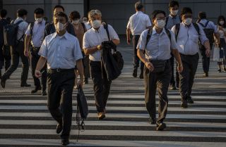 People wearing face masks cross a street on July 28, 2021, in Tokyo, Japan. 